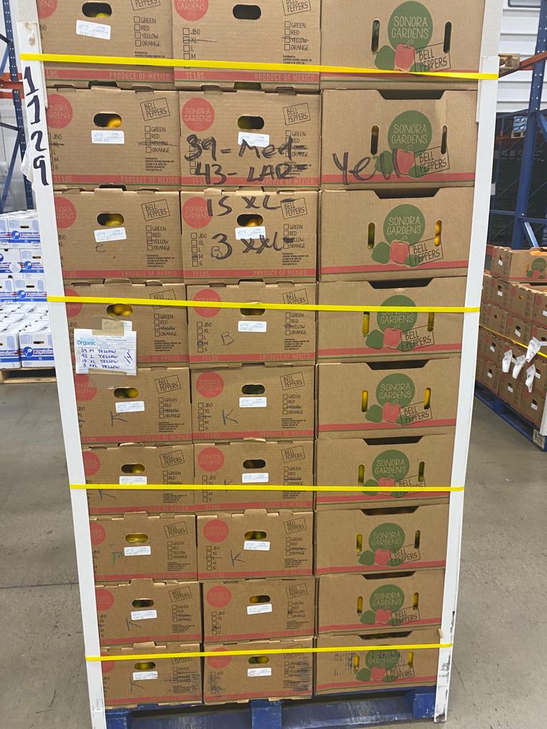 Una tarima flejada de cajas impresas Sonora Gardens de pimiento morrón, con fruta amarilla visible a través de las asas