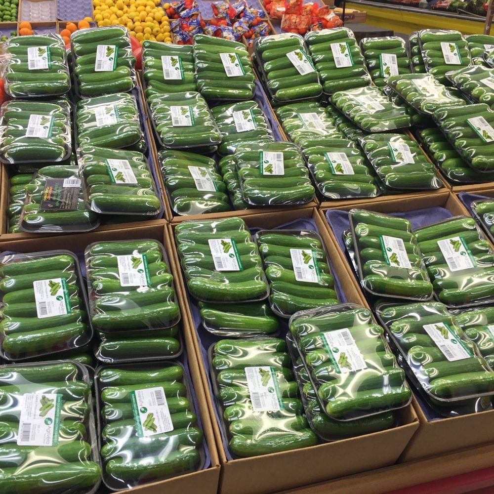 Overwrapped six-packs of Agrivera mini cucumbers in their shipper trays, filling a supermarket display